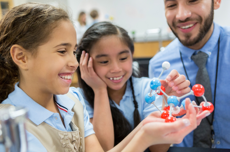 Supervised by Male Teacher Two Girls Play With Plastic Molecules
